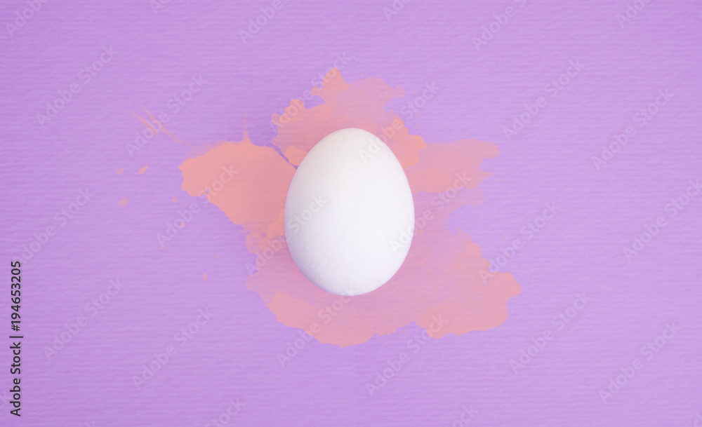 One white egg on violet background with orange watercolor splatters.