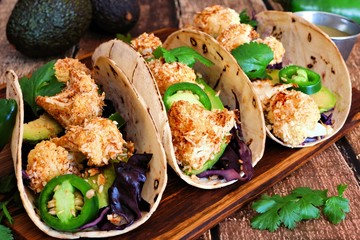 Roasted coconut cauliflower tacos. Healthy, vegan meal. Close up, side view on a wooden background.
