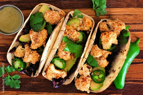 Roasted coconut cauliflower tacos. Healthy, vegan meal. Top view on a wooden background.