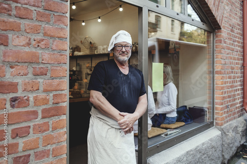 Portrait of senior male baker standing at bakery photo