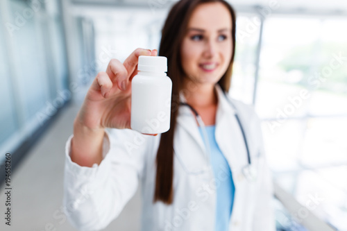 Young female doctor holds blank bottle