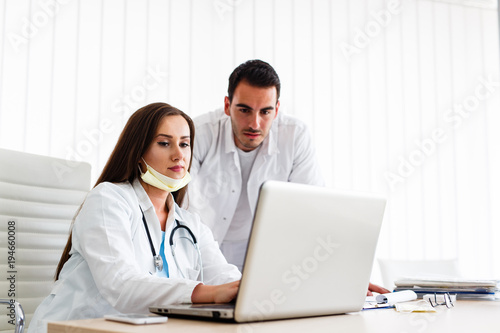 Beautiful nurse and young doctor works on laptop