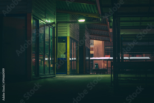 Central marketplace at night time. Isolated territory filled with trading stands and lighten by city lights. Spooky and abandoned atmosphere in urban market territory. 