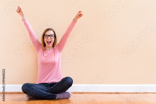 Happy young woman cheering with her arms in the air