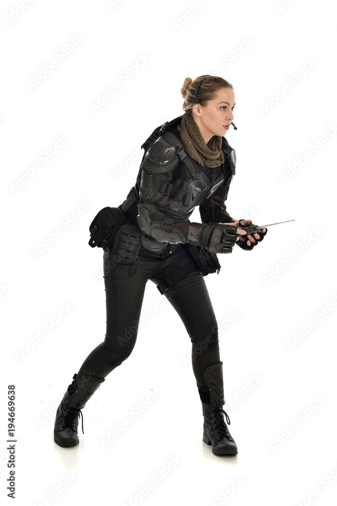 full length portrait of female soldier wearing black tactical armour, holding a remote control, isolated on white studio background. full length portrait of female soldier wearing black tactical armour, holding a remote control, isolated on white studio background.