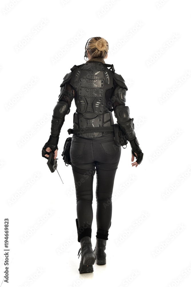 full length portrait of female soldier wearing black tactical armour, holding a remote control, isolated on white studio background. full length portrait of female soldier wearing black tactical armour, holding a remote control, isolated on white studio background.