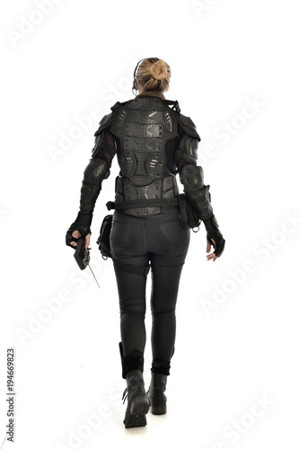 full length portrait of female  soldier wearing black  tactical armour, holding a remote control, isolated on white studio background. © faestock