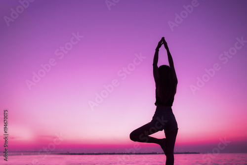 Silhouette of woman practice yoga on beach of sunset background