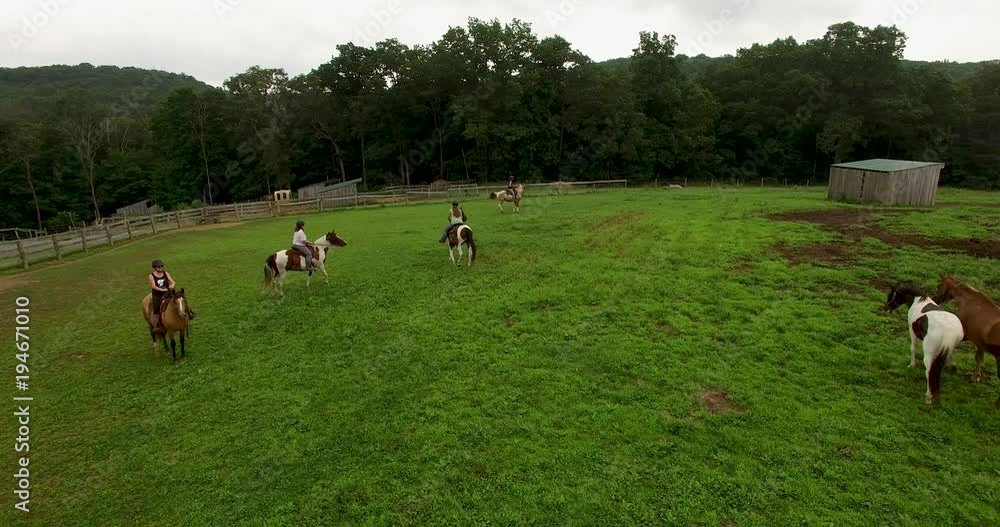 Four female horseback riders ride their horses in a meadow with mountains in the distance on a summer day in Virginia. Four female horseback riders ride their horses in a meadow with mountains in the distance on a summer day in Virginia.