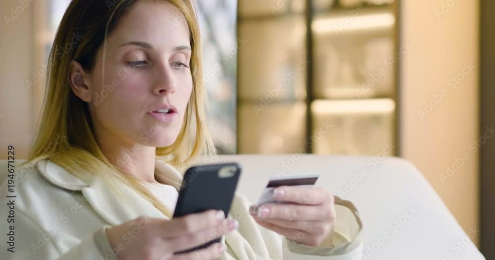 A woman at home is shopping online using the phone and entering credit card information. The woman is happy with her online purchases. Concept of: shopping, shipping, app and technology A woman at home is shopping online using the phone and entering credit card information. The woman is happy with her online purchases. Concept of: shopping, shipping, app and technology