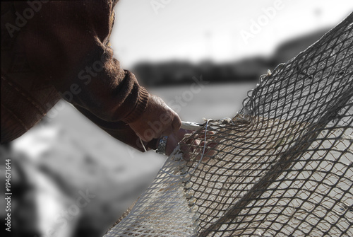 hands of a fisherman repairing a fish-net