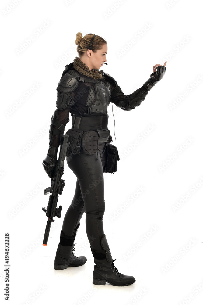 full length portrait of female soldier wearing black tactical armour, holding a rifle gun, isolated on white studio background. full length portrait of female soldier wearing black tactical armour, holding a rifle gun, isolated on white studio background.