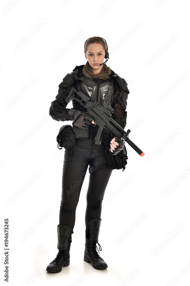 full length portrait of female soldier wearing black tactical armour, holding a rifle gun, isolated on white studio background. full length portrait of female soldier wearing black tactical armour, holding a rifle gun, isolated on white studio background.