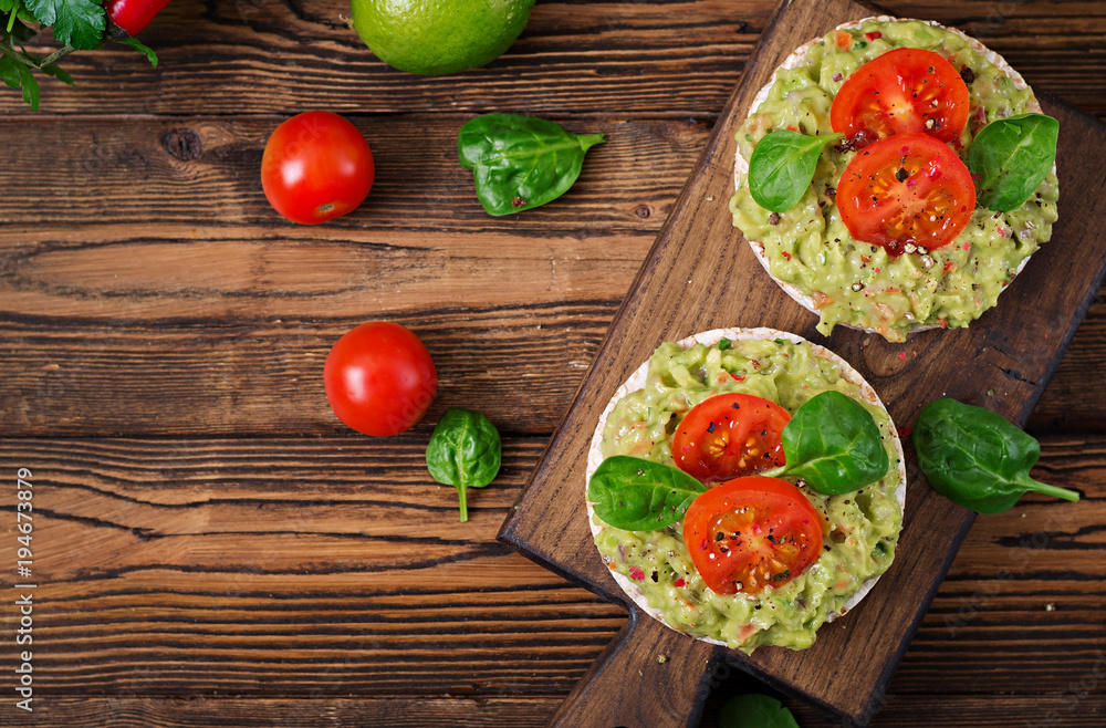 Healthy breakfast. Sandwich crisp bread with guacamole and tomatoes on a wooden background. Healthy breakfast. Sandwich crisp bread with guacamole and tomatoes on a wooden background.