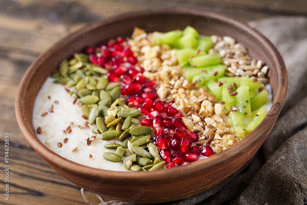 Delicious and healthy oatmeal with kiwi, pomegranate and seeds. Healthy breakfast. Fitness food. Proper nutrition. Rustic style Delicious and healthy oatmeal with kiwi, pomegranate and seeds. Healthy breakfast. Fitness food. Proper nutrition. Rustic style