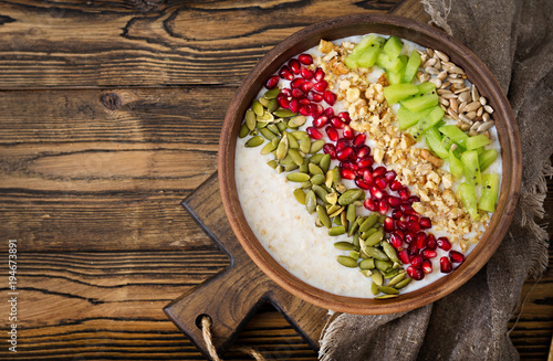 Delicious and healthy oatmeal with kiwi, pomegranate and seeds. Healthy breakfast. Fitness food. Proper nutrition. Rustic style. Flat lay. Top view