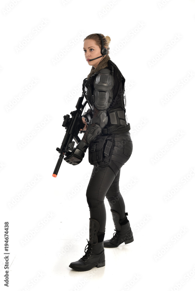 full length portrait of female soldier wearing black tactical armour, holding a rifle gun, isolated on white studio background. full length portrait of female soldier wearing black tactical armour, holding a rifle gun, isolated on white studio background.