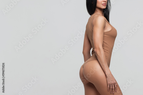 Fitness girl with perfect body shapes on a gray background