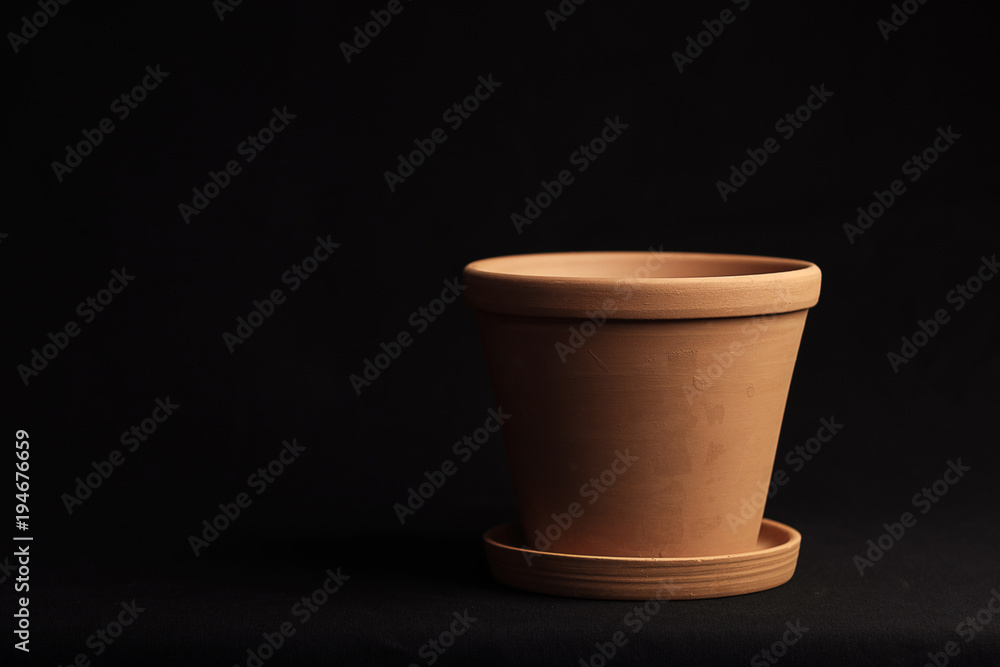 clay pot empty on a black background, part of the pot goes into the dark clay pot empty on a black background, part of the pot goes into the dark