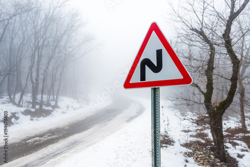 Road sign on road in winter forest