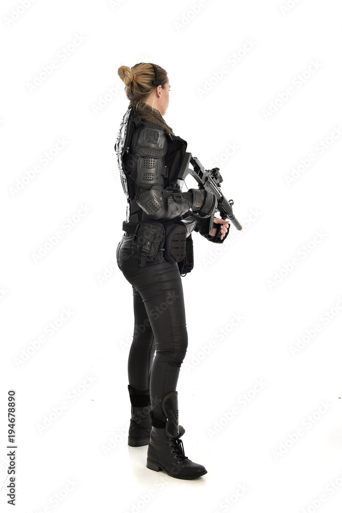 full length portrait of female soldier wearing black tactical armour, holding a rifle gun, isolated on white studio background. full length portrait of female soldier wearing black tactical armour, holding a rifle gun, isolated on white studio background.