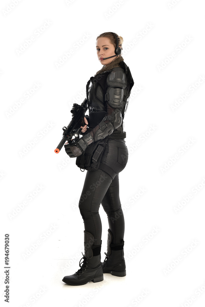 full length portrait of female soldier wearing black tactical armour, holding a rifle gun, isolated on white studio background. full length portrait of female soldier wearing black tactical armour, holding a rifle gun, isolated on white studio background.