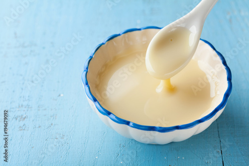 Foto Bowl with pouring condensed milk or evaporated milk.