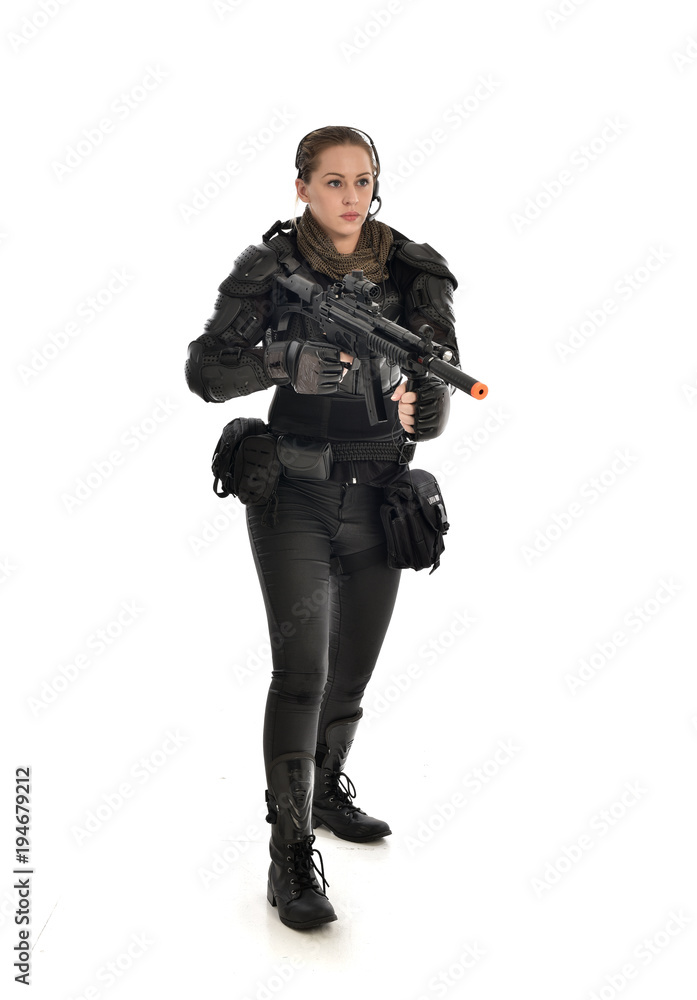 full length portrait of female soldier wearing black tactical armour, holding a rifle gun, isolated on white studio background. full length portrait of female soldier wearing black tactical armour, holding a rifle gun, isolated on white studio background.