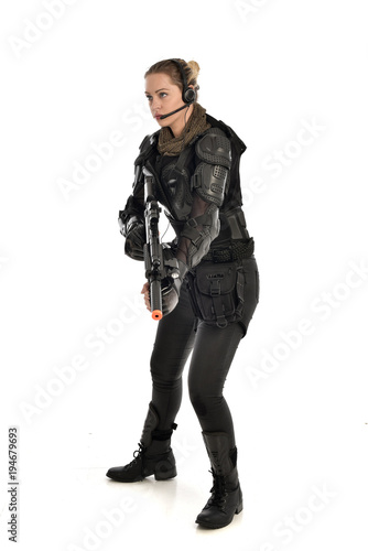 full length portrait of female soldier wearing black tactical armour, holding a rifle gun, isolated on white studio background.
