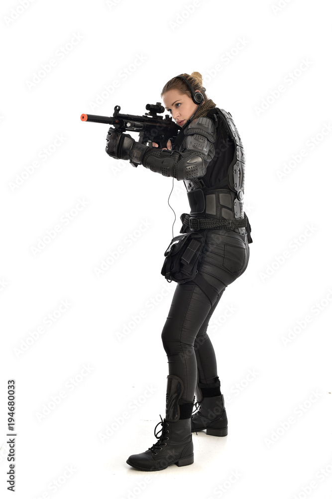 full length portrait of female soldier wearing black tactical armour, holding a rifle gun, isolated on white studio background. full length portrait of female soldier wearing black tactical armour, holding a rifle gun, isolated on white studio background.