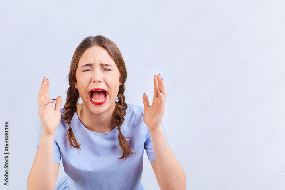 Young girl screams with emotion excited looking at gray background.