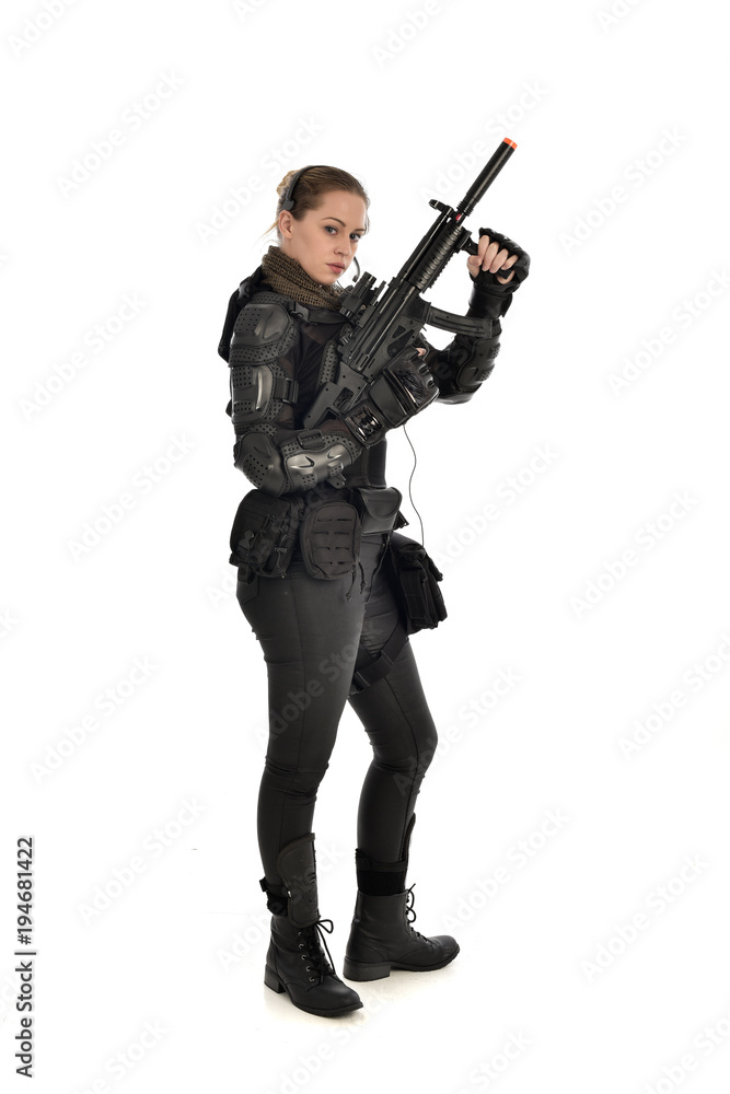 full length portrait of female soldier wearing black tactical armour, holding a rifle gun, isolated on white studio background. full length portrait of female soldier wearing black tactical armour, holding a rifle gun, isolated on white studio background.