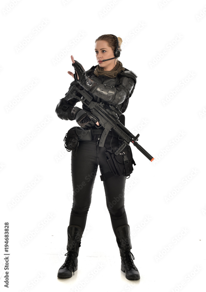full length portrait of female soldier wearing black tactical armour, holding a rifle gun, isolated on white studio background. full length portrait of female soldier wearing black tactical armour, holding a rifle gun, isolated on white studio background.