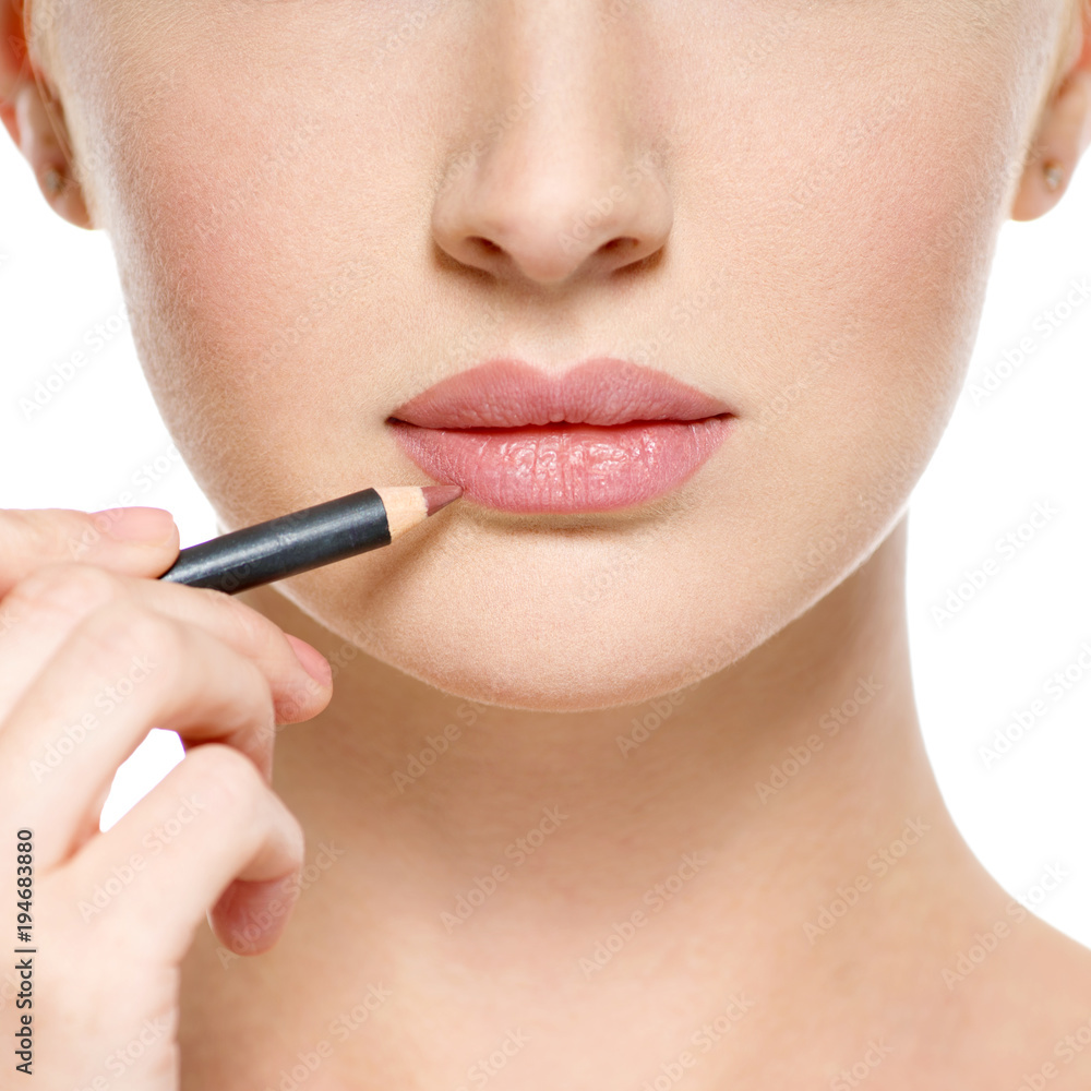 Girl apply lipstick with cosmetic pencil on the lips