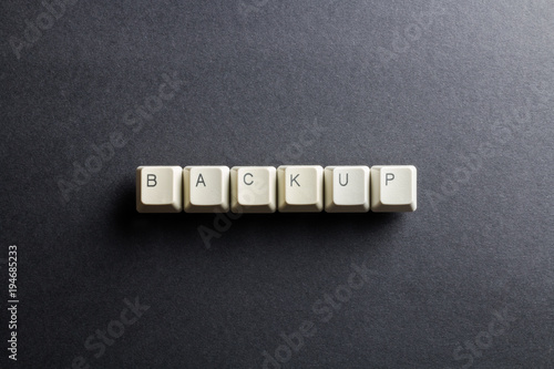 Word backup made using computer keyboard buttons on a black background. IT technology concept.