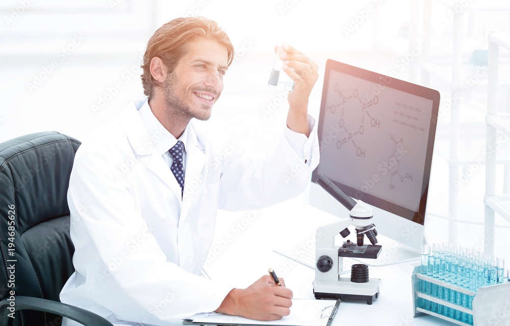 scientist in the chemical lab examines a flask with a substance scientist in the chemical lab examines a flask with a substance