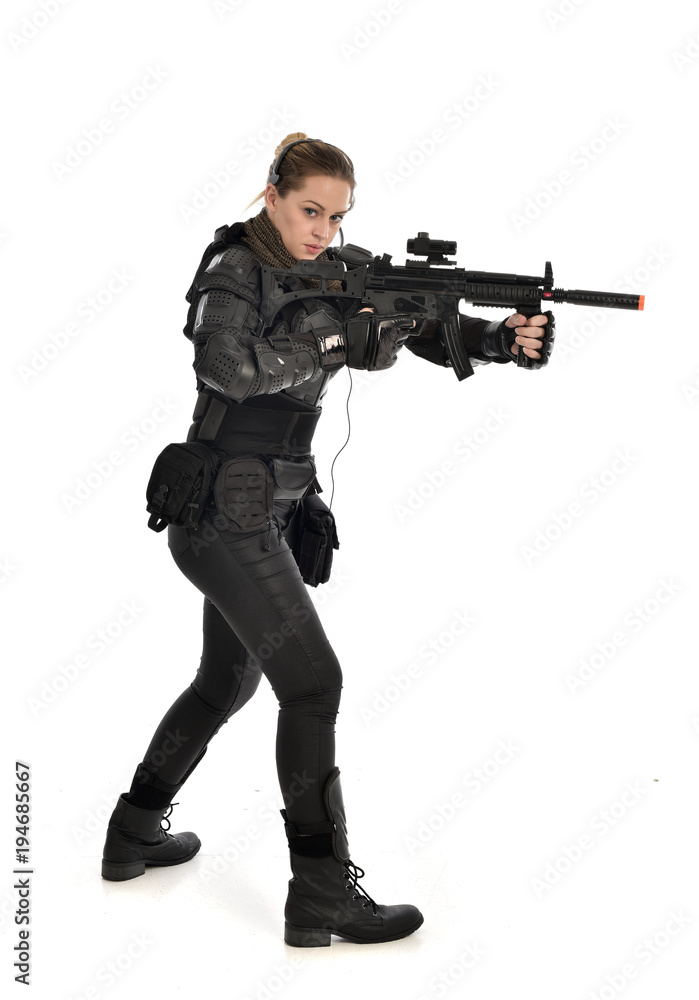 full length portrait of female soldier wearing black tactical armour, holding a rifle gun, isolated on white studio background. full length portrait of female soldier wearing black tactical armour, holding a rifle gun, isolated on white studio background.