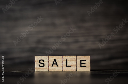 the word sale, consisting of light wooden cubes on a dark wooden background