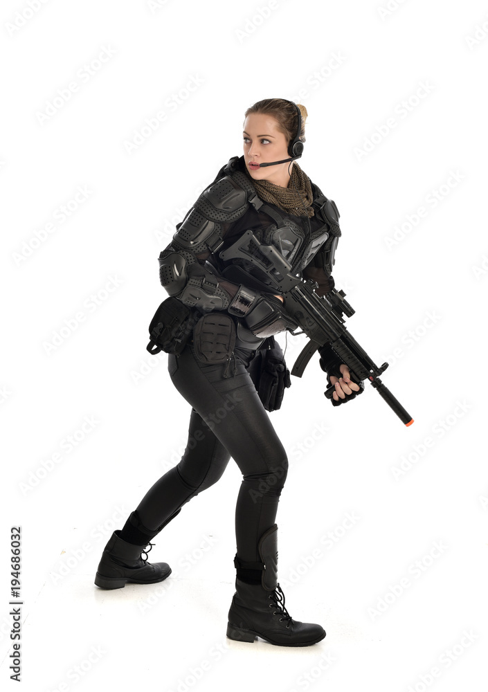 full length portrait of female soldier wearing black tactical armour, holding a rifle gun, isolated on white studio background. full length portrait of female soldier wearing black tactical armour, holding a rifle gun, isolated on white studio background.