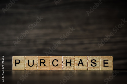 the word purchase, consisting of light wooden cubes on a dark wooden background