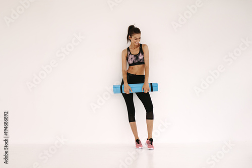 Sportswoman with yoga mat in fitness studio