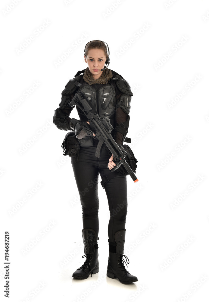 full length portrait of female soldier wearing black tactical armour, holding a rifle gun, isolated on white studio background. full length portrait of female soldier wearing black tactical armour, holding a rifle gun, isolated on white studio background.