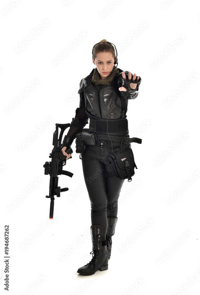 full length portrait of female soldier wearing black tactical armour, holding a rifle gun, isolated on white studio background. full length portrait of female soldier wearing black tactical armour, holding a rifle gun, isolated on white studio background.