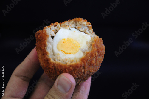 Traditional british food. Half eaten Scotch egg. Hard boiled-egg wrapped in sausage meat coated in bread crumbs and baked or deep-fried. Common picnic food in United Kingdom