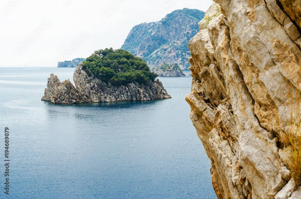 Fototapeta premium Desert island in the sea and rocks summer panorama of rest in the background of mountains in sea bay blue calm mood on vocation wild nature