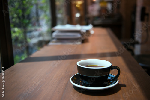 Hot coffee cup on wooden table with books background in vintage tone