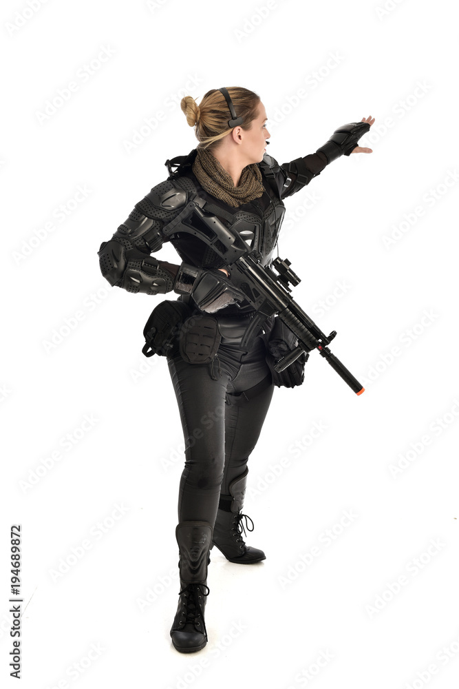 full length portrait of female soldier wearing black tactical armour, holding a rifle gun, isolated on white studio background. full length portrait of female soldier wearing black tactical armour, holding a rifle gun, isolated on white studio background.
