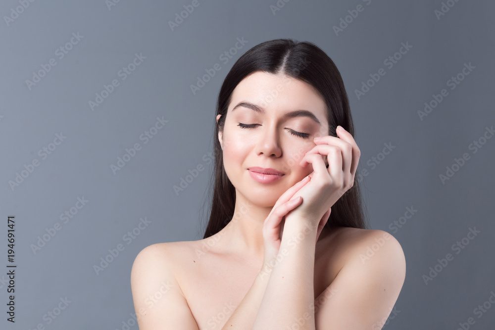 Beautiful woman face and hands close up on grey studio background Beautiful woman face and hands close up on grey studio background