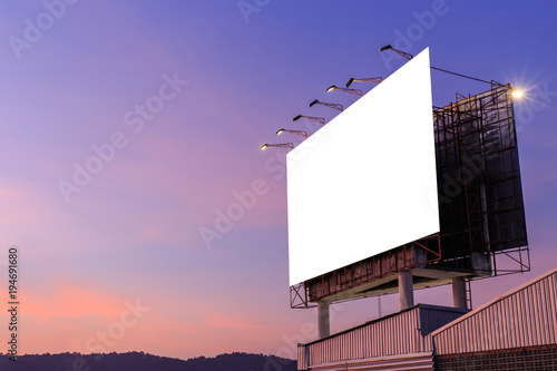 Large white advertising billboard on top of the building and sky background in sunset time. For design and advertisement concept
