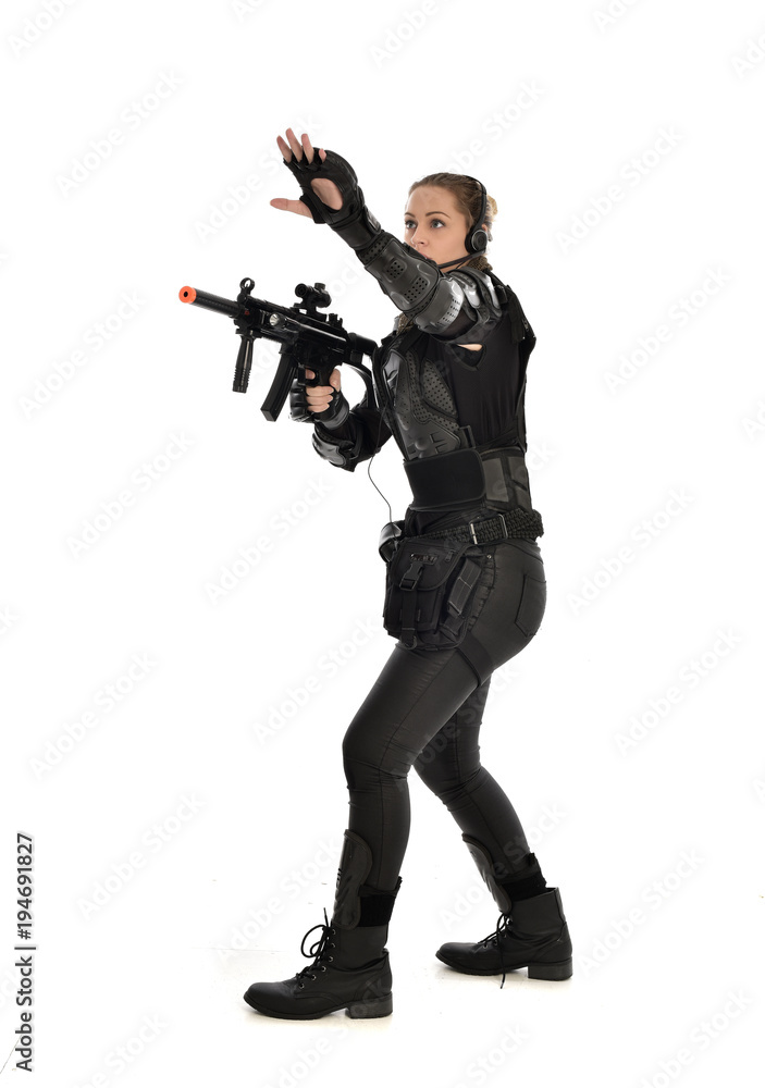 full length portrait of female soldier wearing black tactical armour, holding a rifle gun, isolated on white studio background. full length portrait of female soldier wearing black tactical armour, holding a rifle gun, isolated on white studio background.